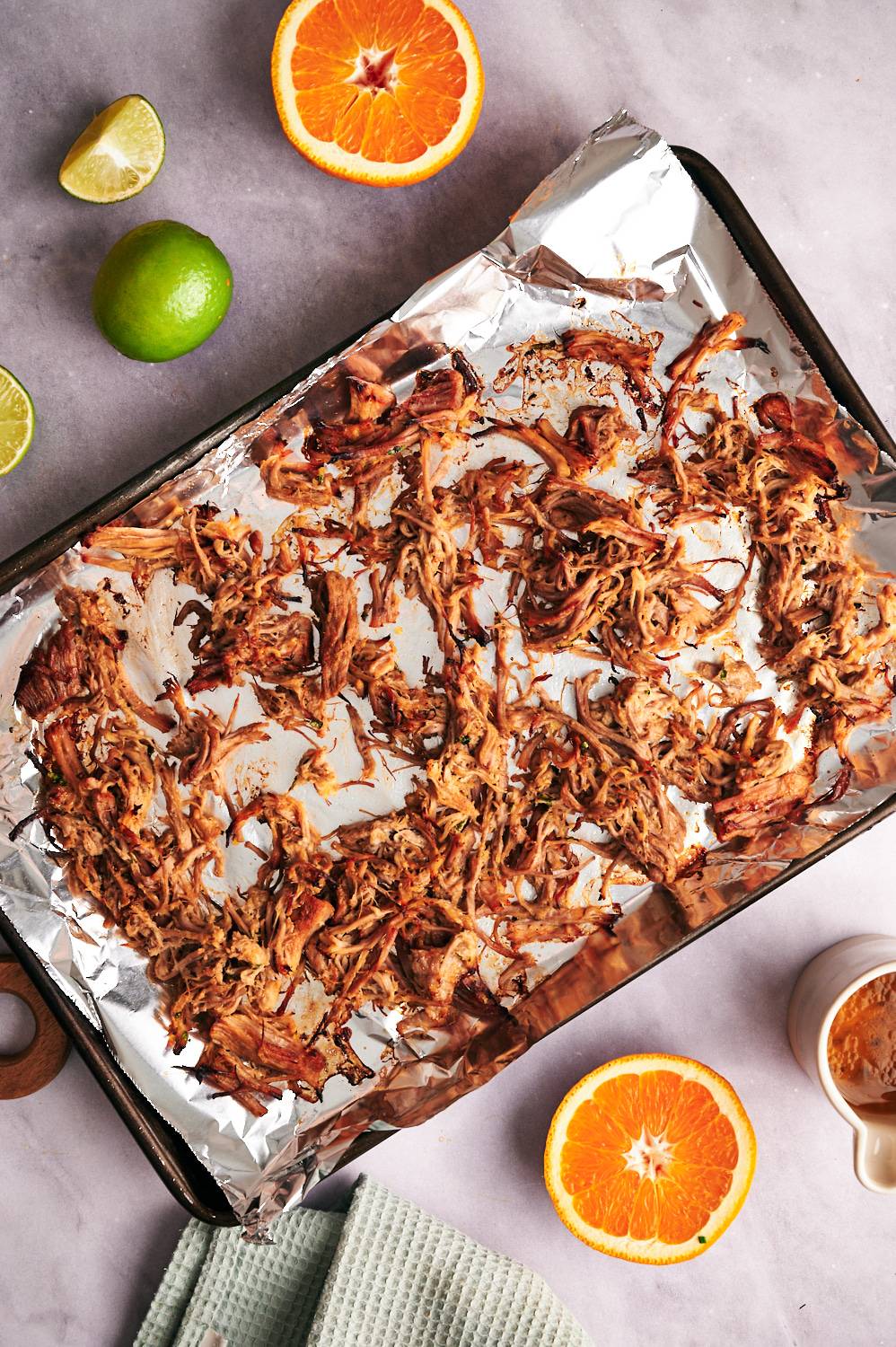 Pork carnitas on a baking sheet with crispy, broiled edges.