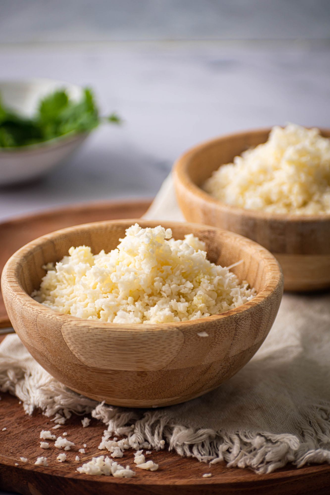 Homemade cauliflower rice made with cauliflower florets cooked in olive oil and served in a wooden bowl.