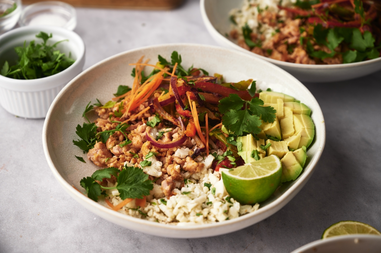 Ground turkey taco bowls with cauliflower rice served in a bowl with cilantro, avocado, and vegetables.