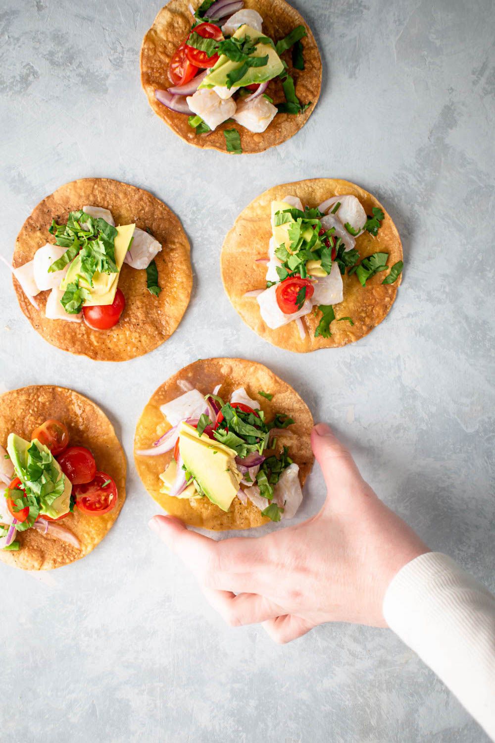 Tostadas with fish ceviche on crispy corn tortillas with ceviche, avocado, cilantro, red onion, and tomatoes.