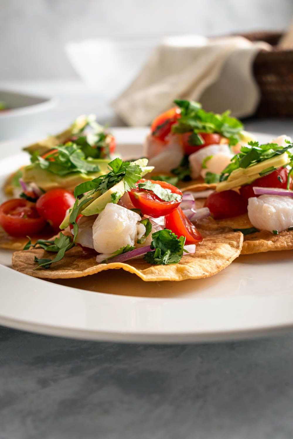 Baked tostadas with fish ceviche served on a plate with avocado, cilantro, and limes.