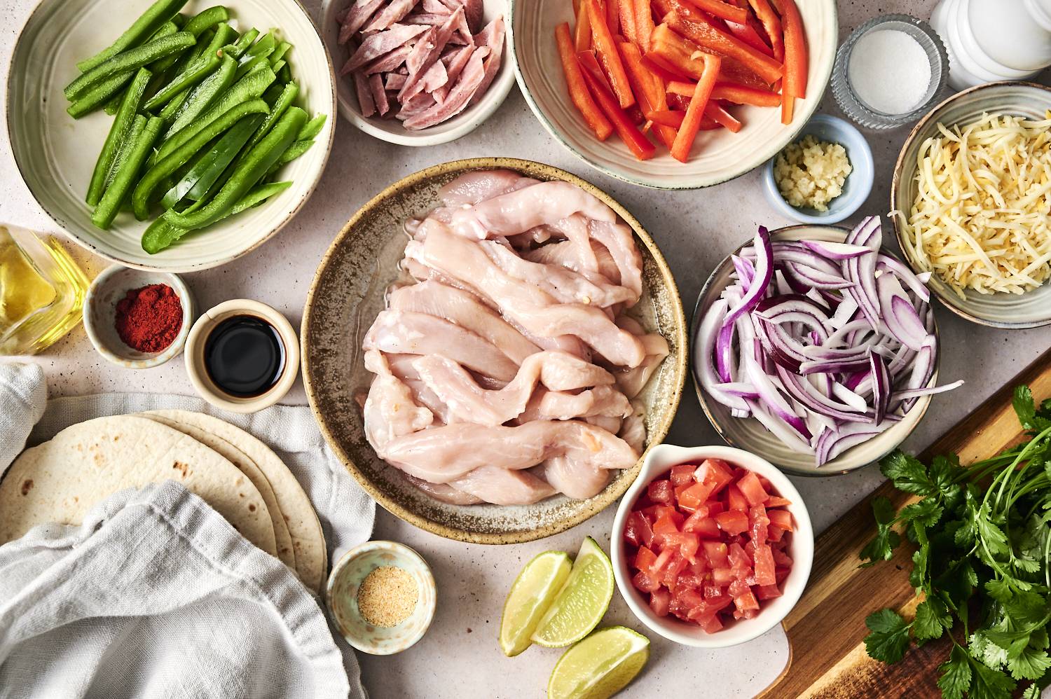 Prepped ingredients, including bell peppers, chicken, and tortillas for chicken alambre tacos.