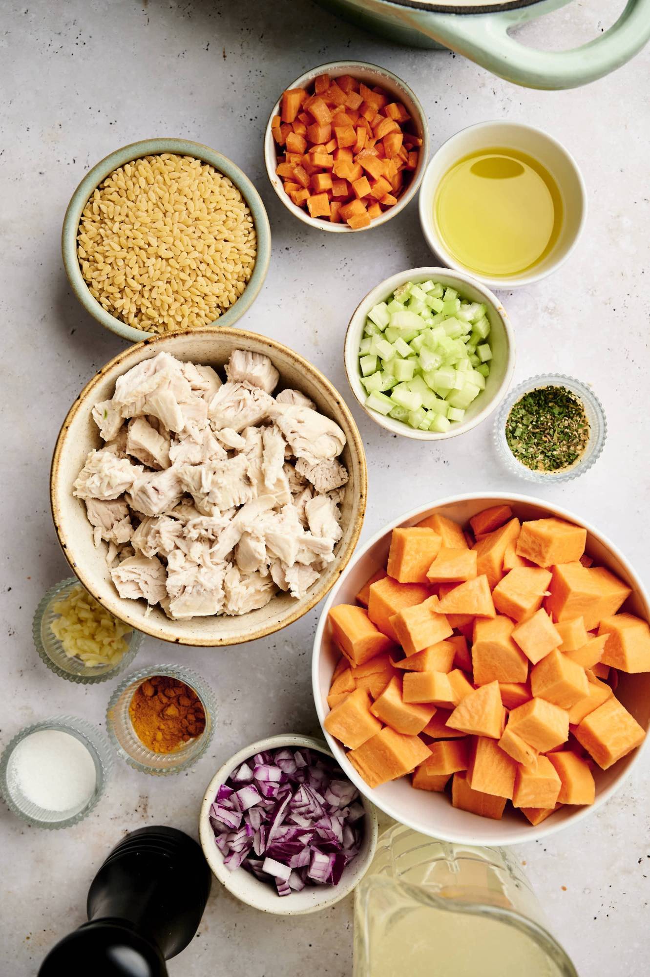 Ingredients for chicken sweet potato soup including cooked chicken, orzo, carrots, celery, onions, sweet potatoes, garlic, and spices.