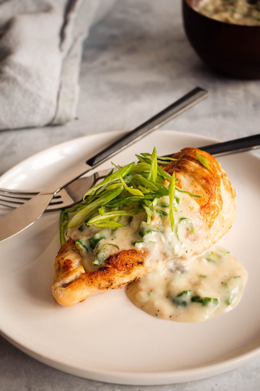 Chicken breast with jalapeno cream cheese and green onions served on a plate with green onions.