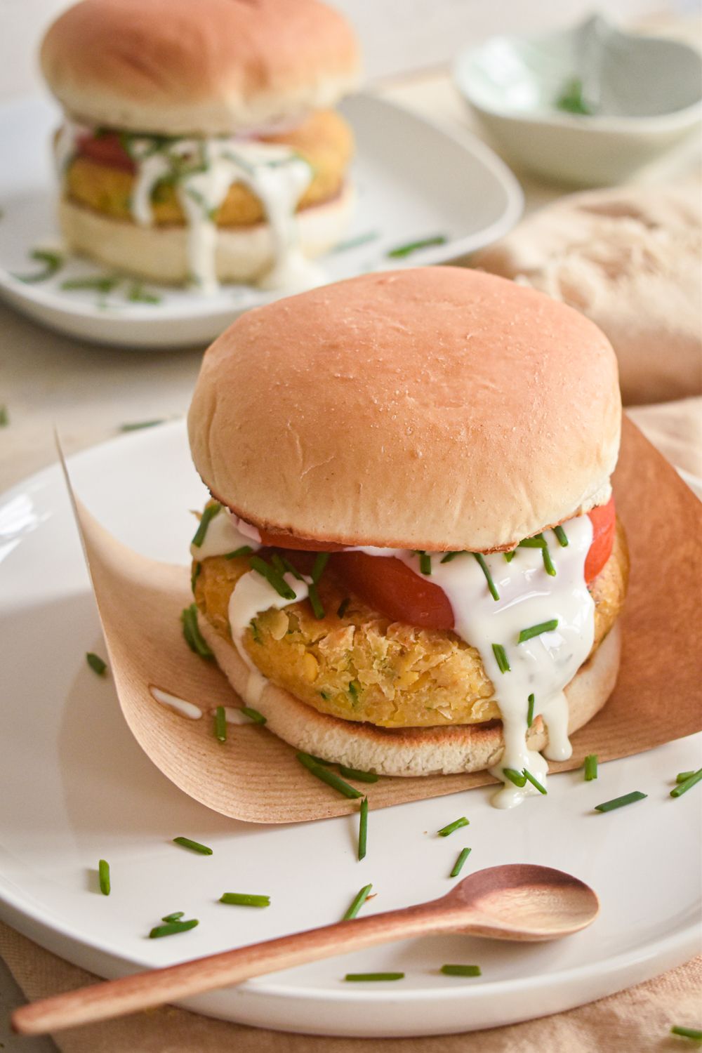 Chickpea burgers with ranch seasoning on a rolll with tomato and ranch dressing.