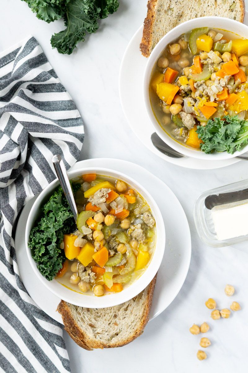 Chickpea, sausage, and butternut squash stew in a bowl with celery, onions, and kale.