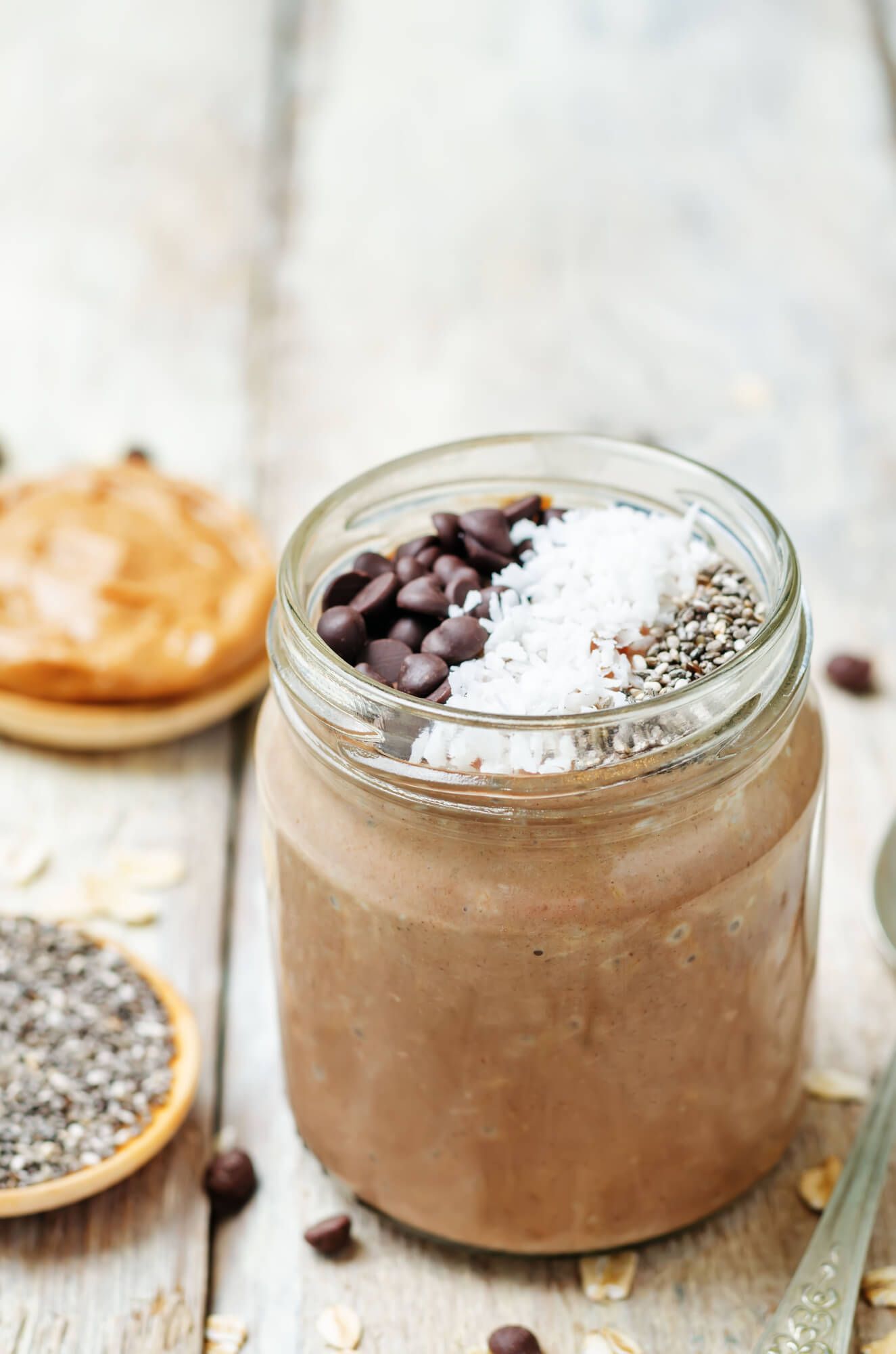 Chocolate chia seed pudding in a glass jar with peanut butter and chia seeds in the background.