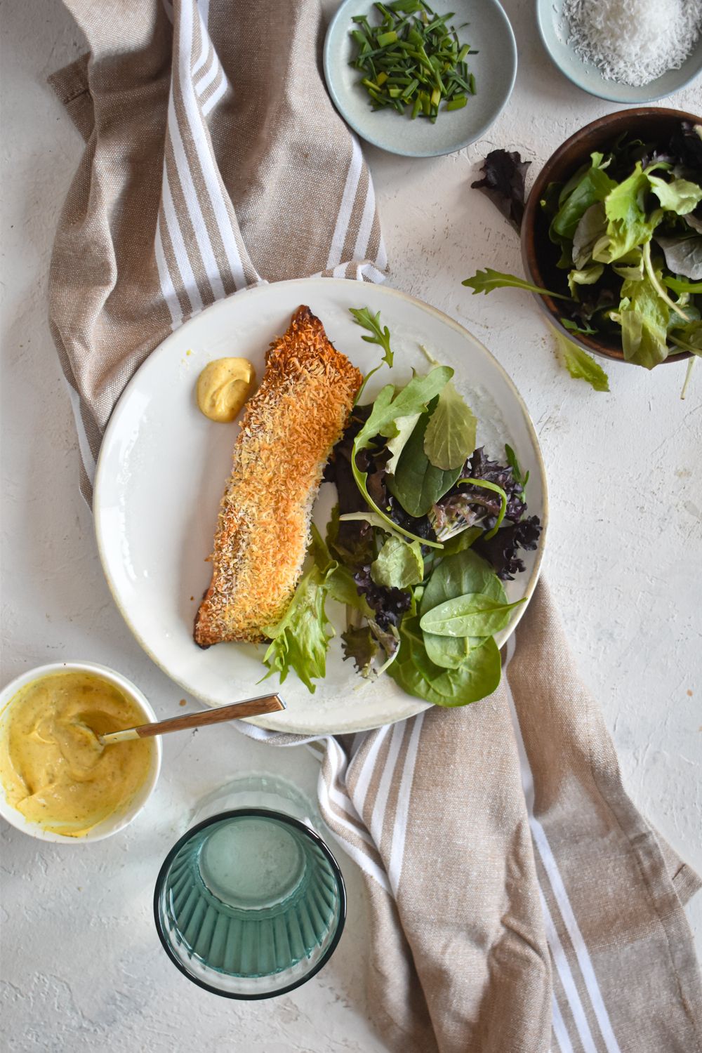Coconut salmon on a plate with greens and honey mustard sauce. 