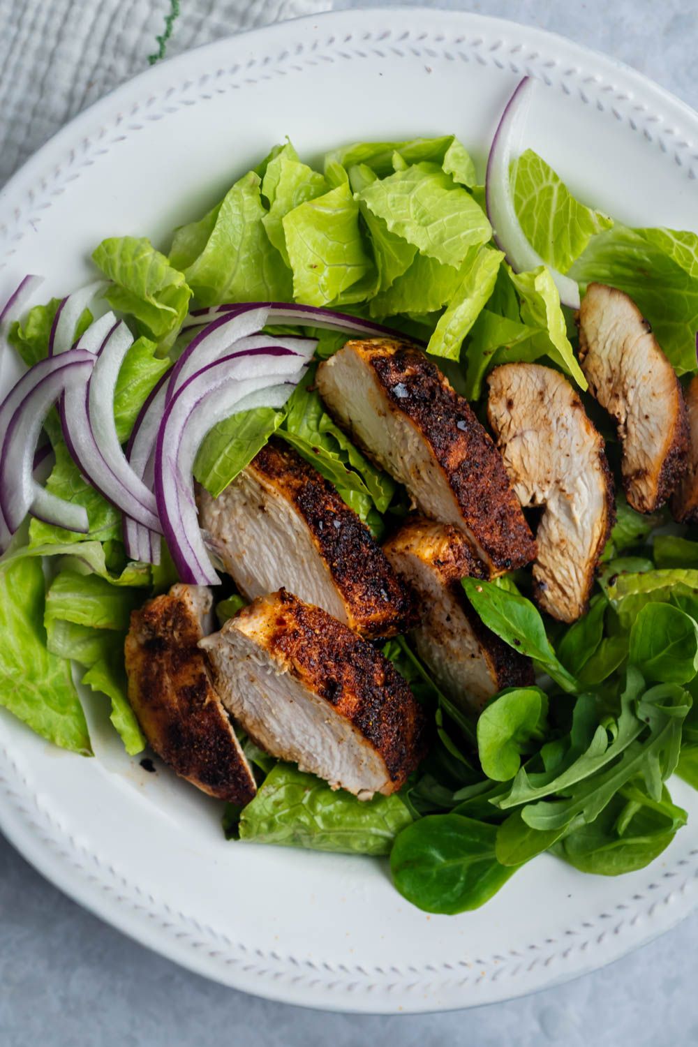 Grilled cumin chicken sliced and served over a bed of greens with red onion and lime juice.