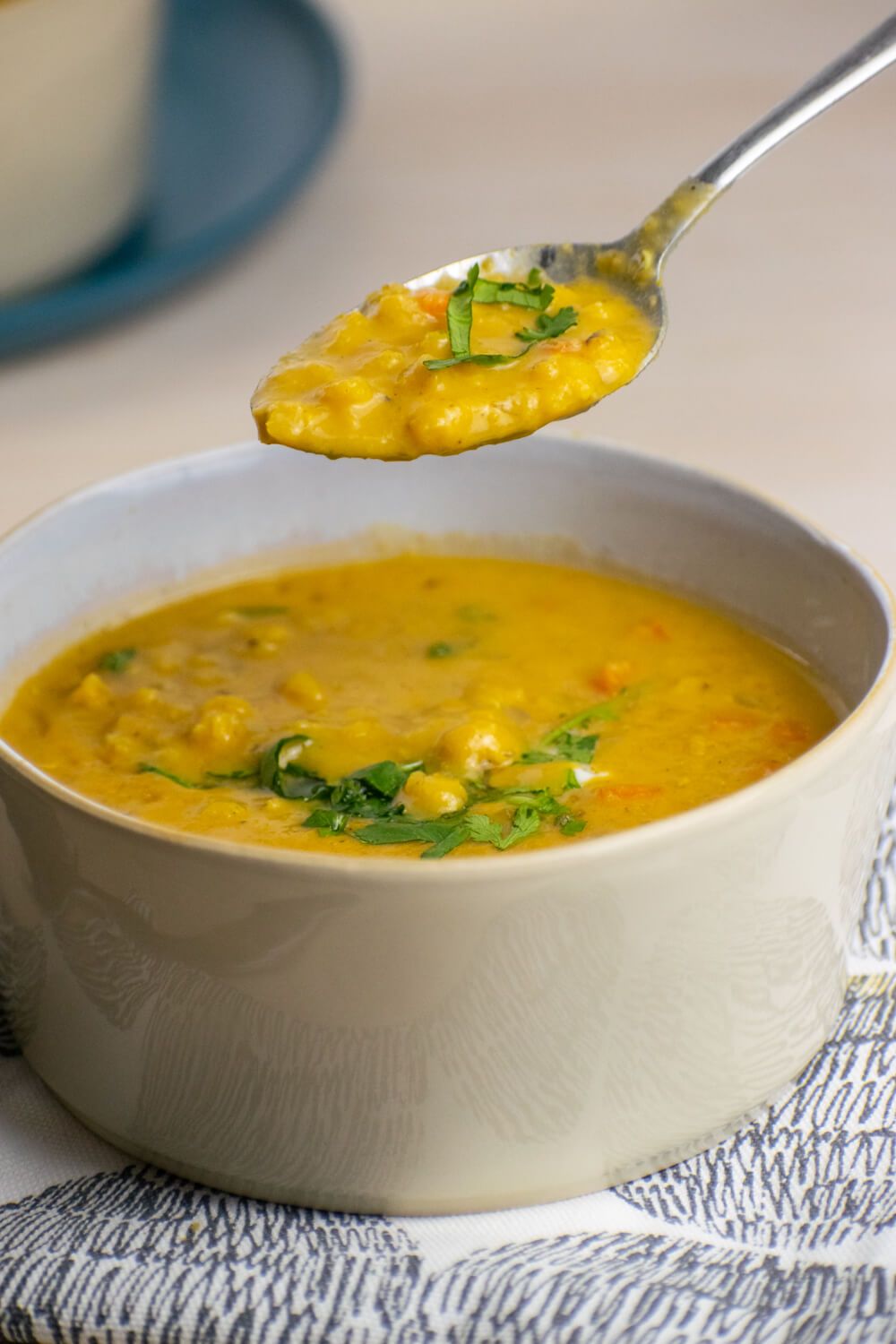 Curried red lentil soup with carrots and curry in a bowl with a spoon.