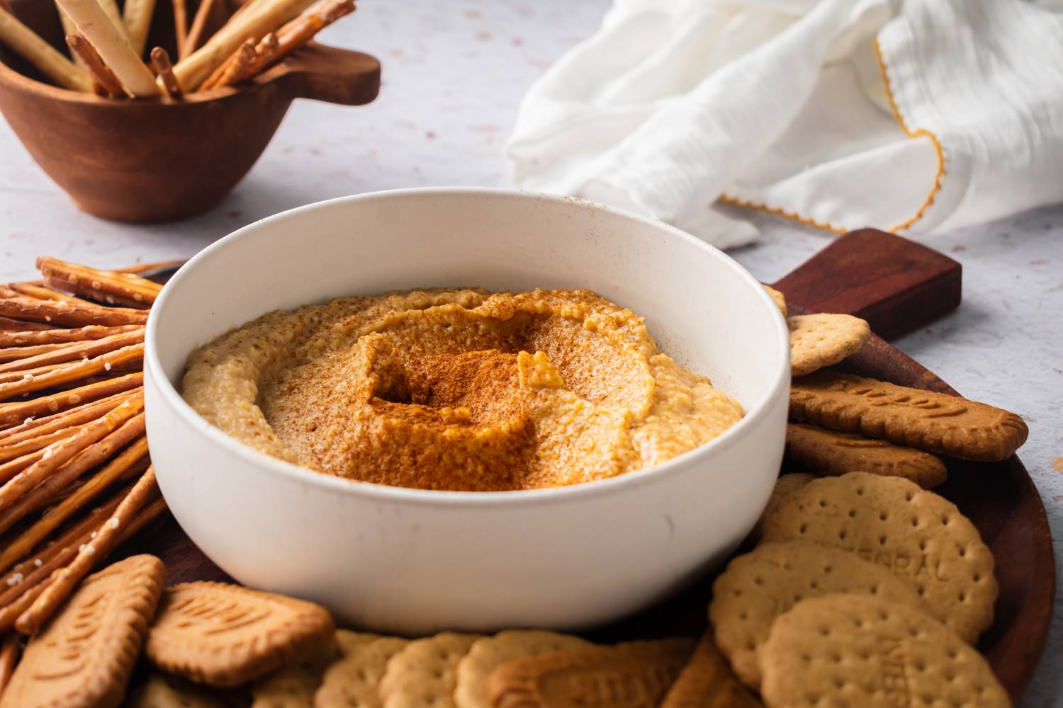 Bowl of sweet dessert hummus with cinnamon served with crackers, pretzels, and cookies.