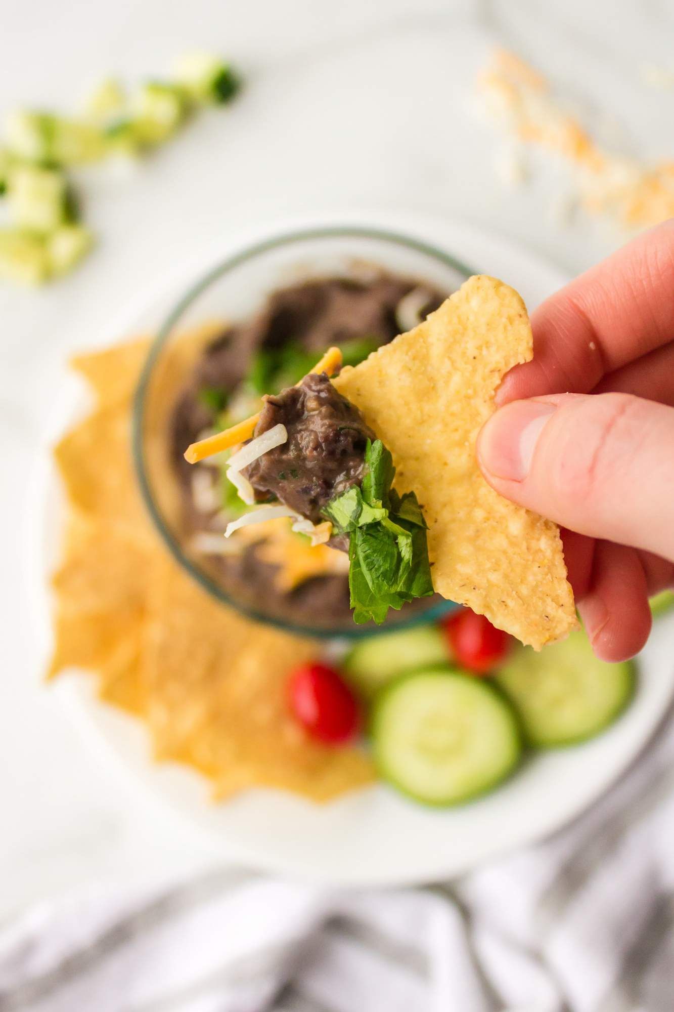 Dip made with black beans scooped up with a chip with cheese and cilantro.