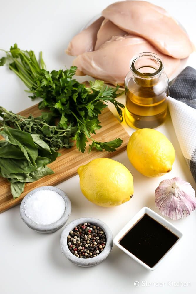 Ingredients for grilled chicken breasts including chicken, olive oil, lemons, herbs, and spices.