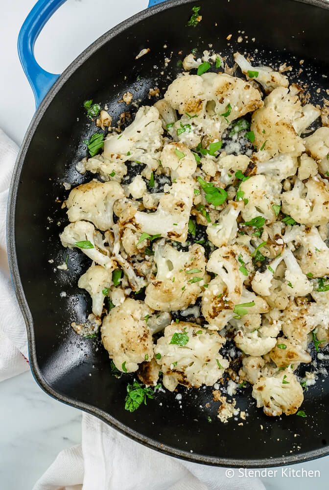 Garlic roasted cauliflower in a skillet with Parmesan cheese, parsley, and lemon