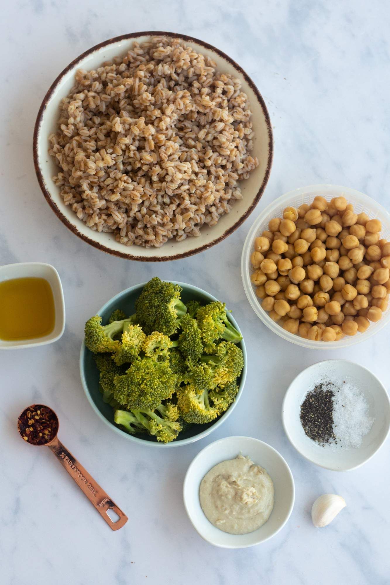 Ingredients for Farro Bowls including cooked farro, broccoli, chickpeas, tahini, and fresh herbs.