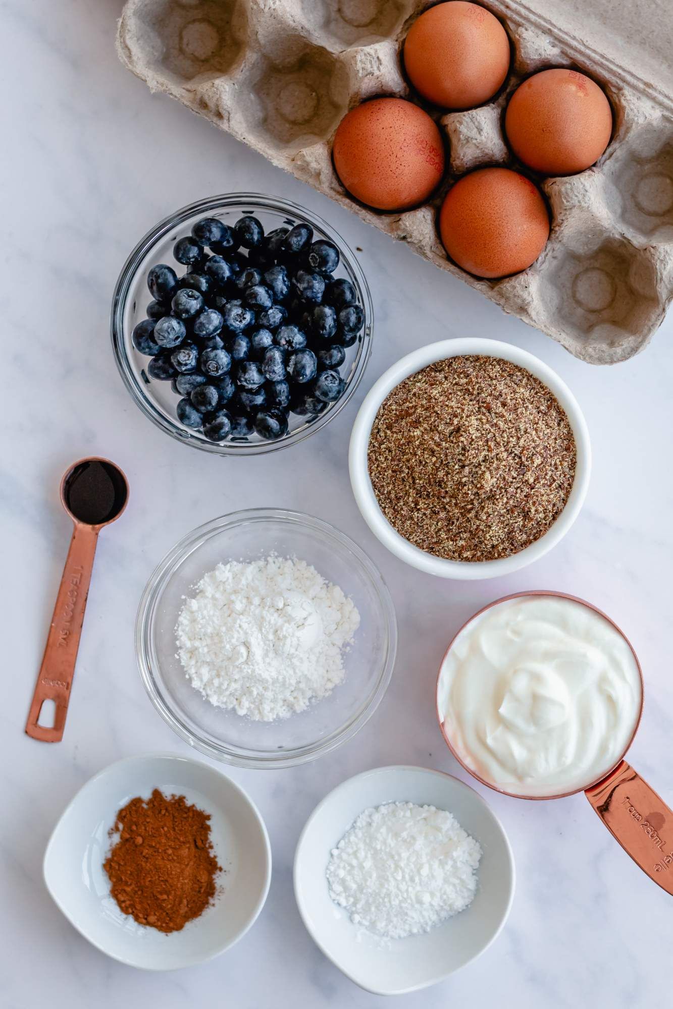 Ingredients for Greek yogurt and flax pancakes with flaxseed meal, yogurt, eggs, blueberries, cinnamon, and baking soda.