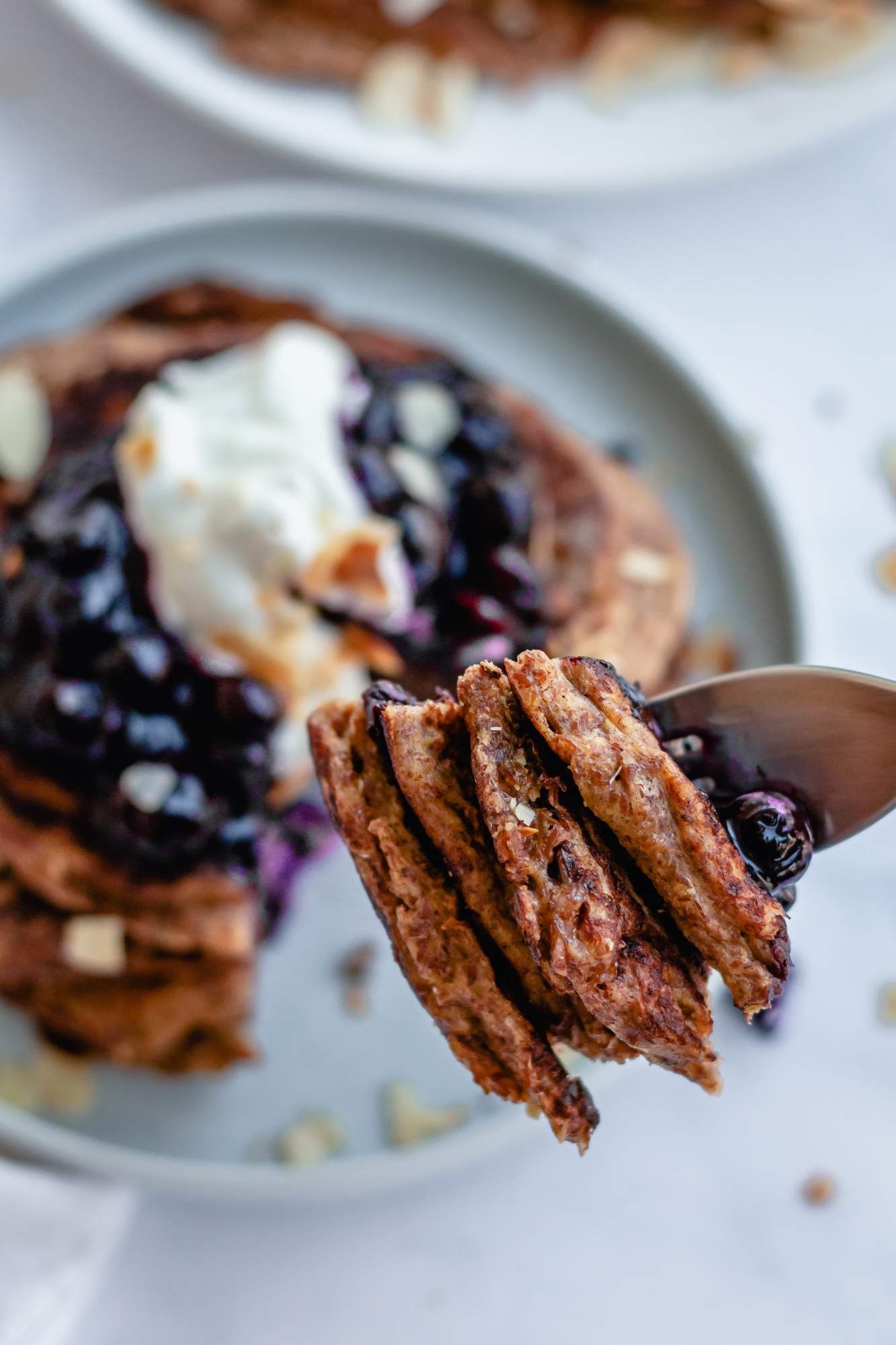 Yogurt and flaxseed pancakes on a fork with blueberries.