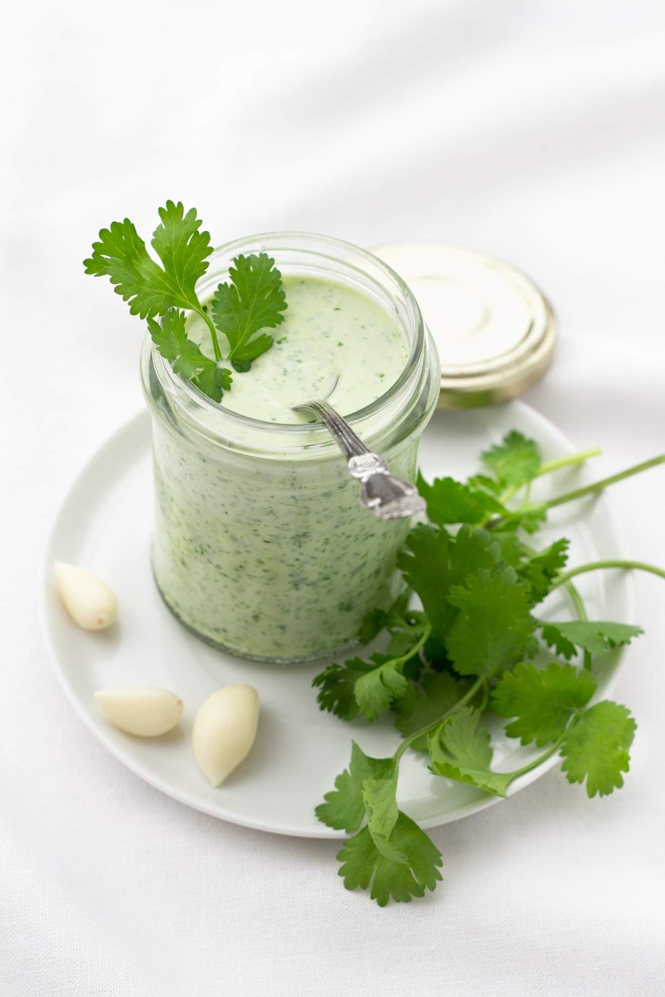 Green goddess dressing in a jar with fresh cilantro, basil, parsley, and garlic.
