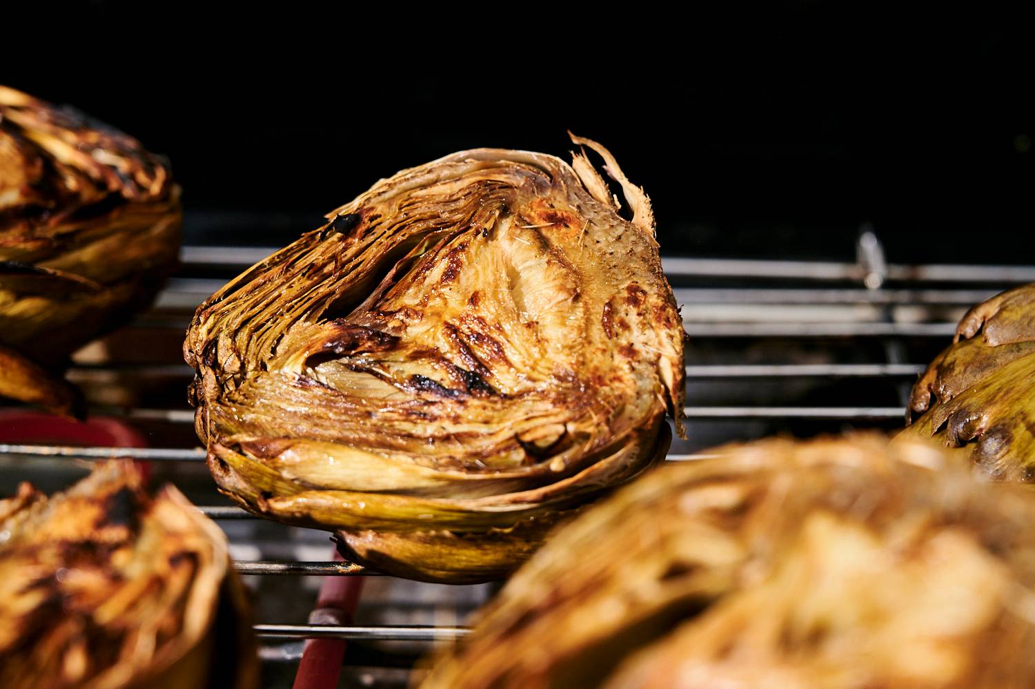 Artichokes on the grill with charred edges.