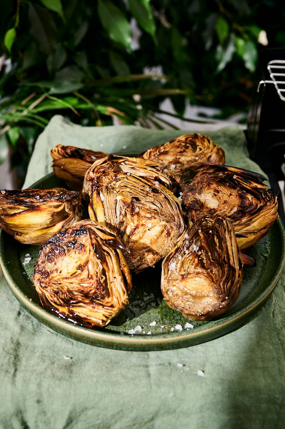 Artichokes with grill marks served on a plate with lemon garlic butter.