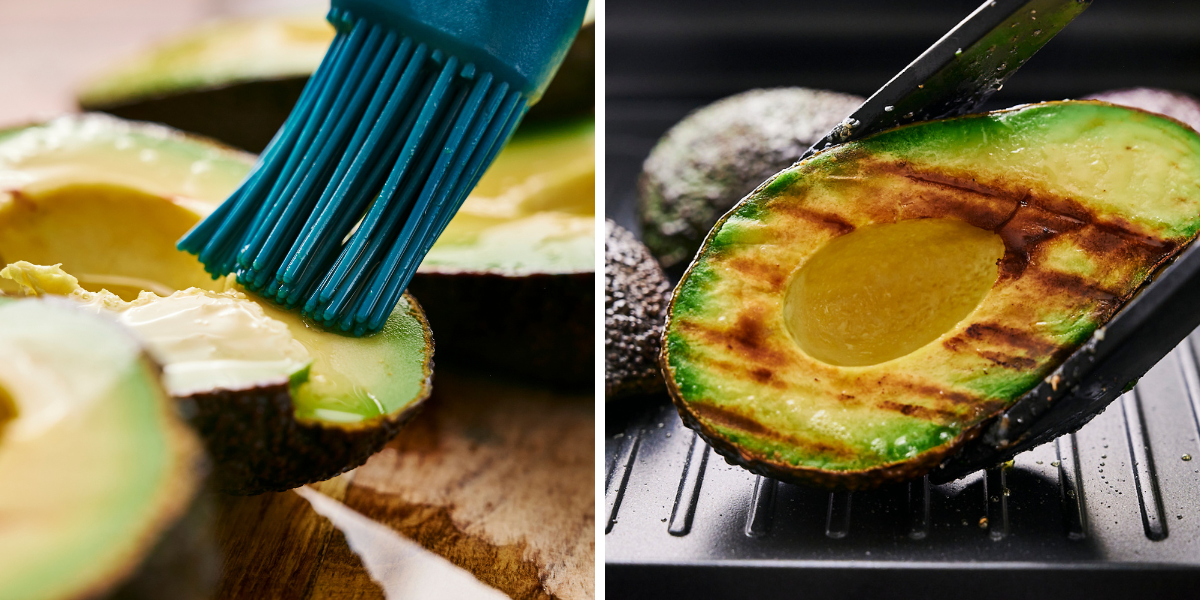A blue brush applies seasoning to a halved avocado, while another grilled avocado is being lifted with tongs, revealing grill marks.