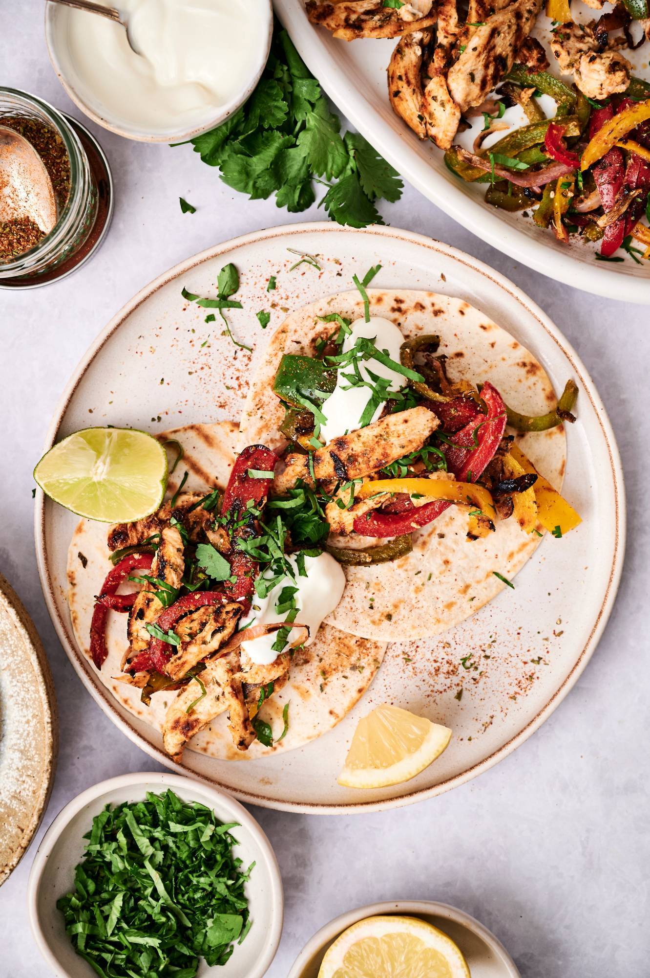 Grilled chicken fajitas served in warm flour tortillas with sour cream cilantro, and lime wedges.