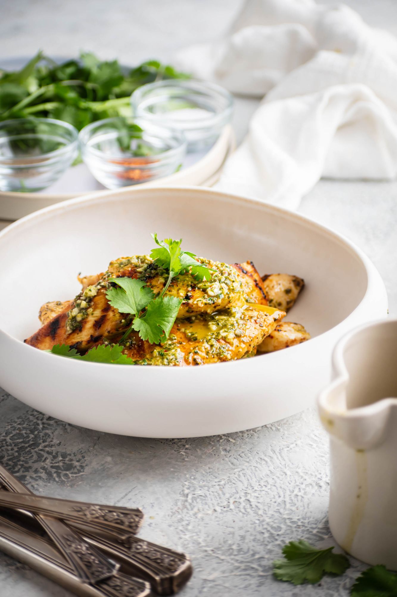 Grilled chicken breast with cilantro lime sauce served in a bowl with fresh cilantro.