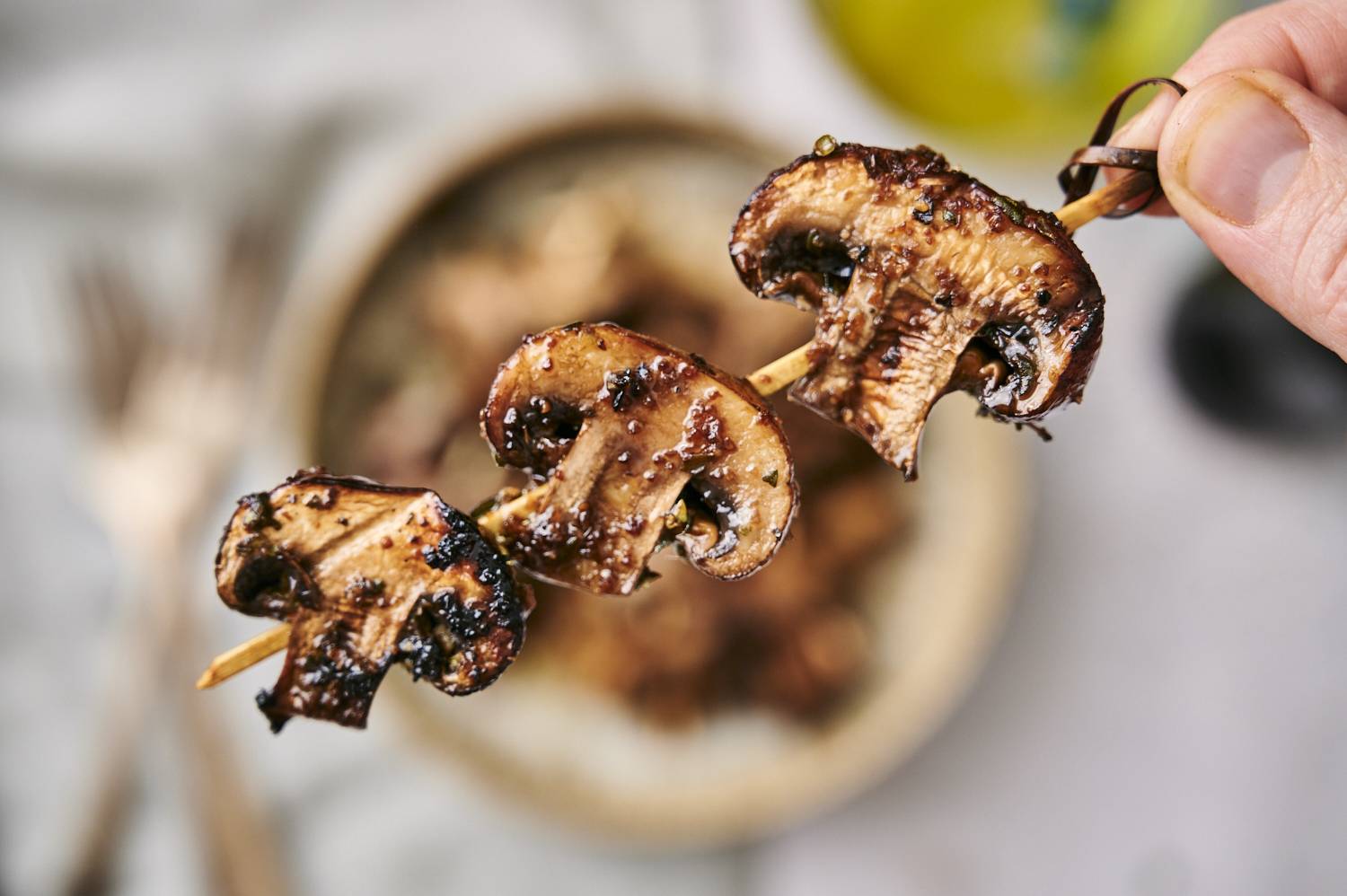 Mushrooms that are grilled with balsamic vinegar and spices on a skewer.