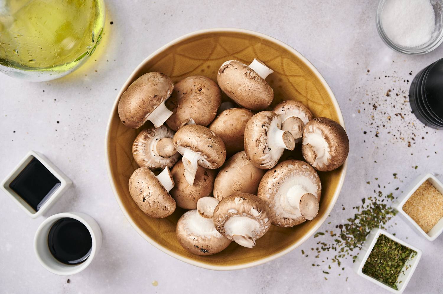 Ingredients for grilled mushrooms including sliced mushrooms, balsamic vinegar, olive oil, garlic powder, and thyme.