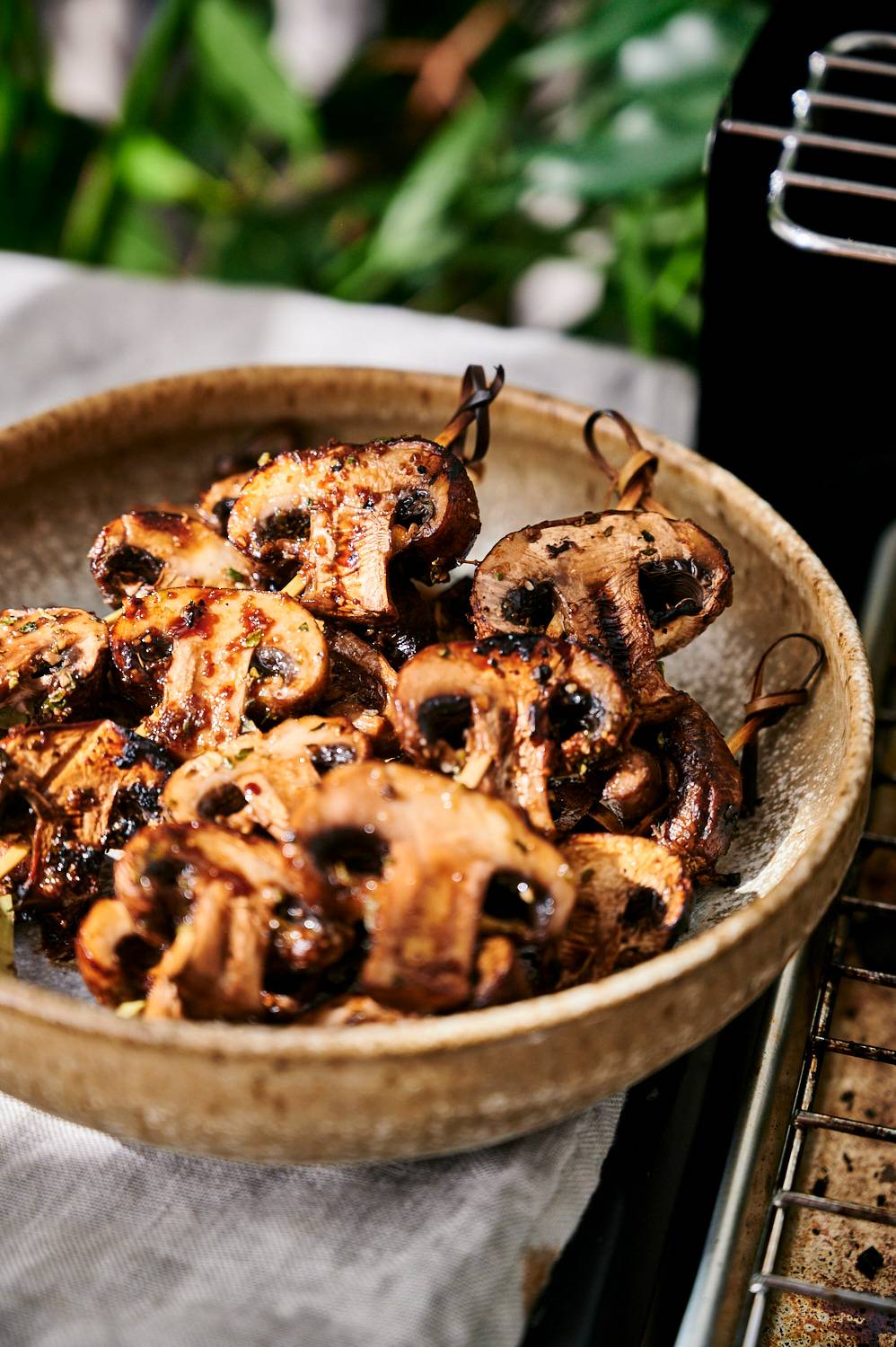 Mushrooms skewers cooked on the grill in a bowl with balsamic vinegar.