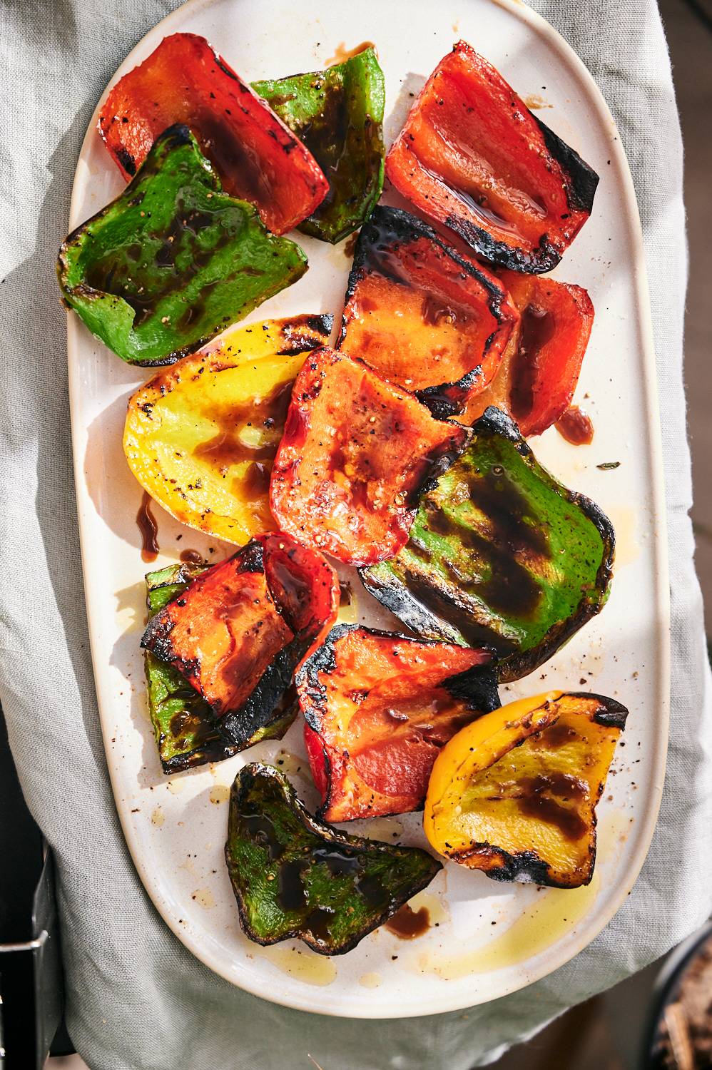 Platter of freshly grilled bell peppers including yellow, green, and red bell peppers.