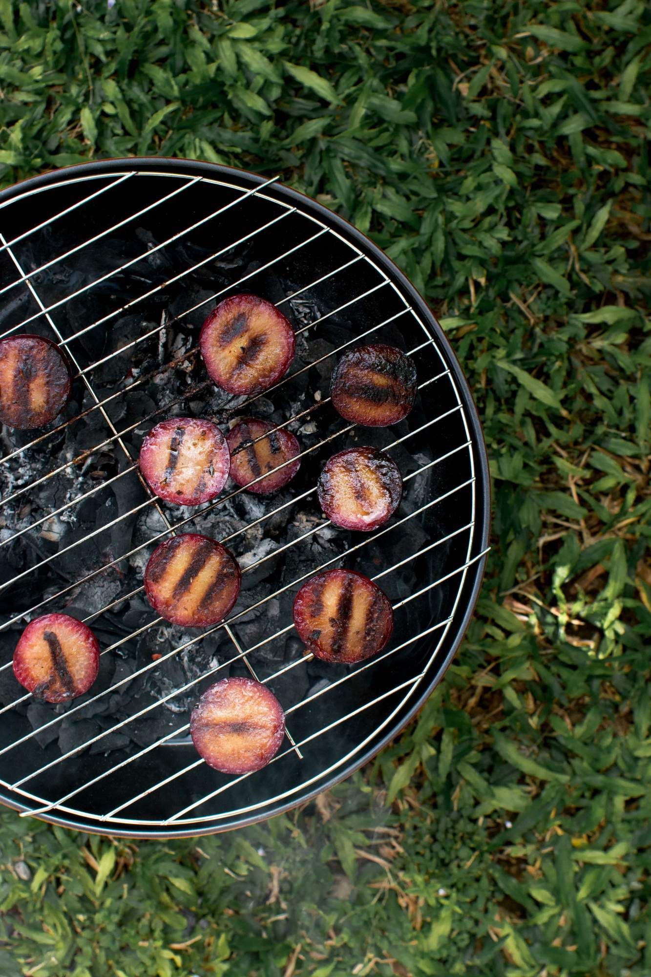 Plums on a grill with grill marks being cooked for a salad.