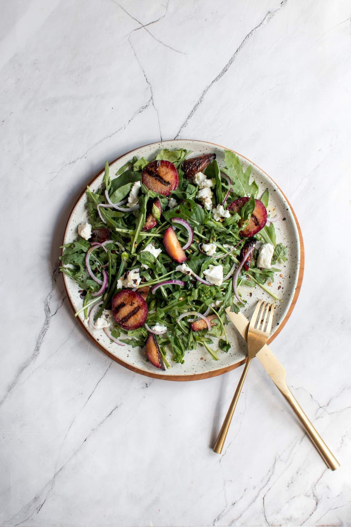 Plum salad with fresh arugula, grilled plums, basil, mint, red onions, goat cheese, and a honey dressing.