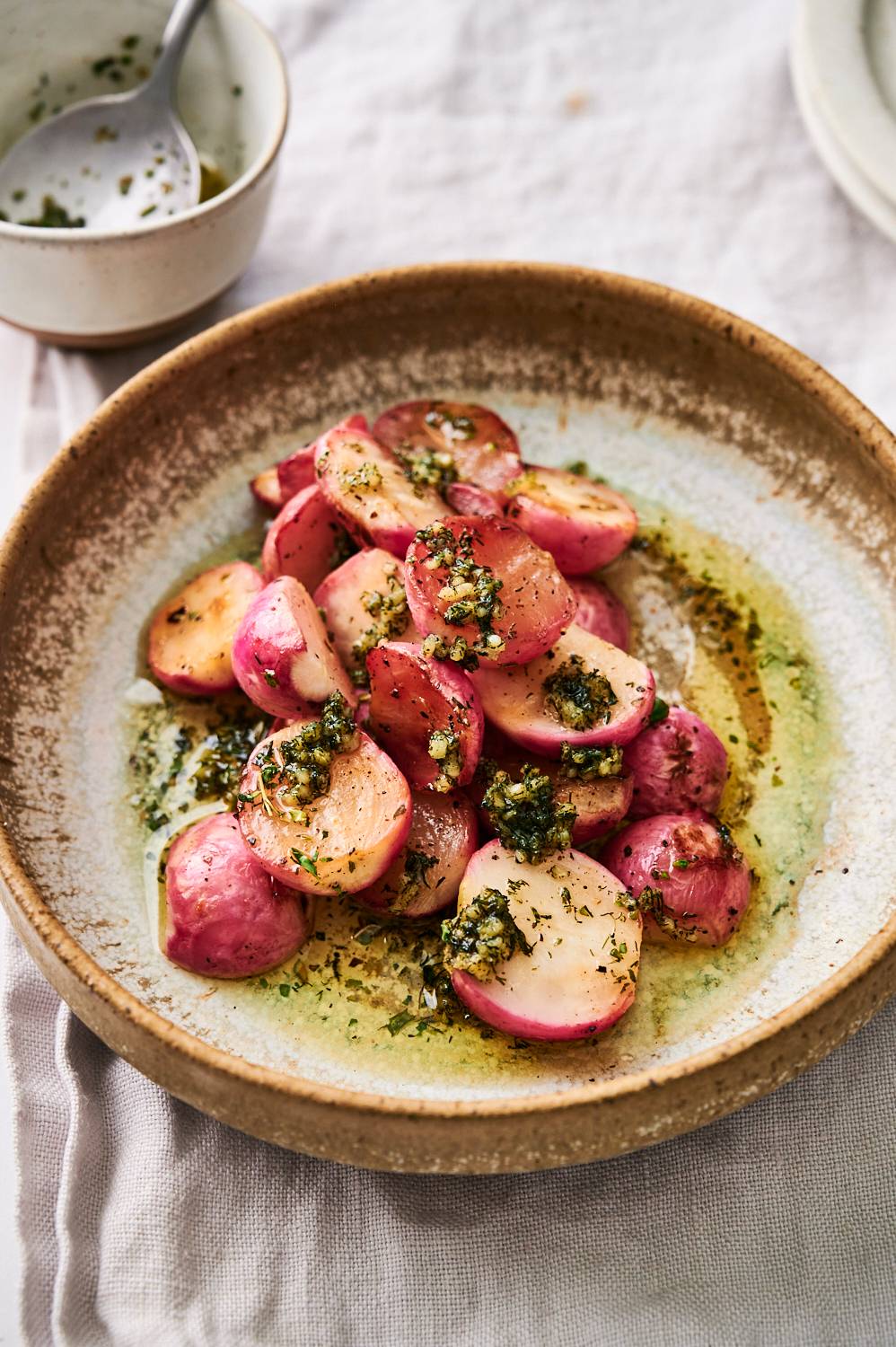 Garlic butter grilled radishes served with chives in a ceramic bowl.