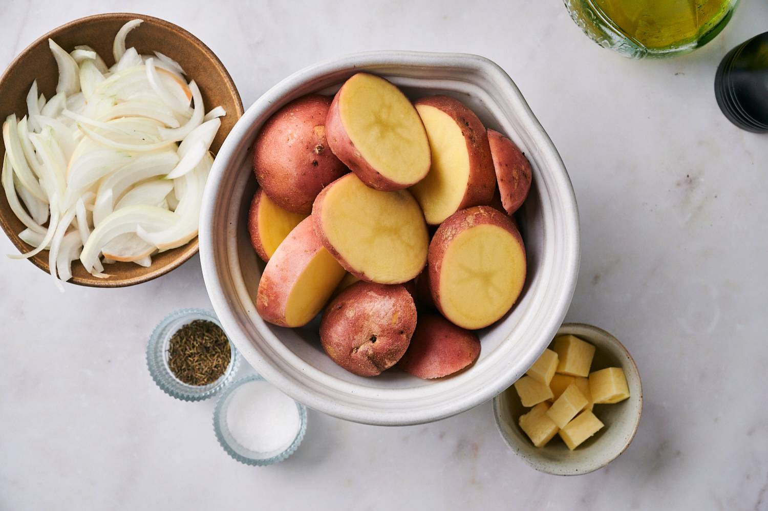 Ingredients for red potatoes including sliced potatoes, onions, butter, salt, pepper, and rosemary.