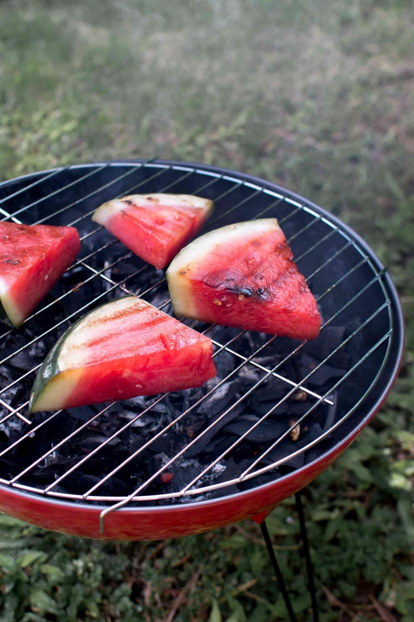 Watermelon on a charcaol grill with grill marks and smoke.