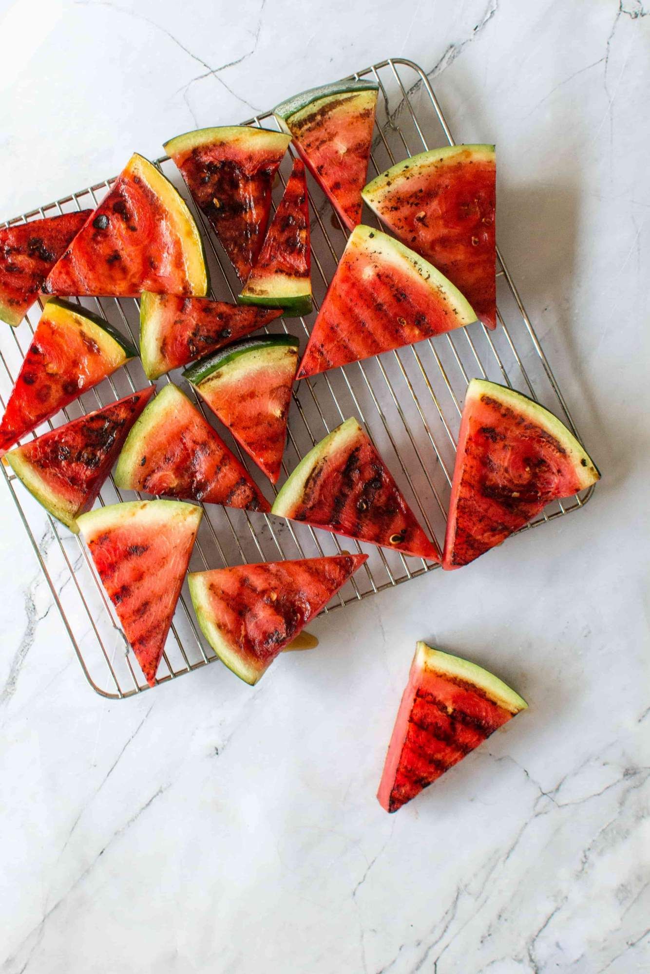 Grilled watermelon slices with fresh mint and salt on a wire rack and plate.