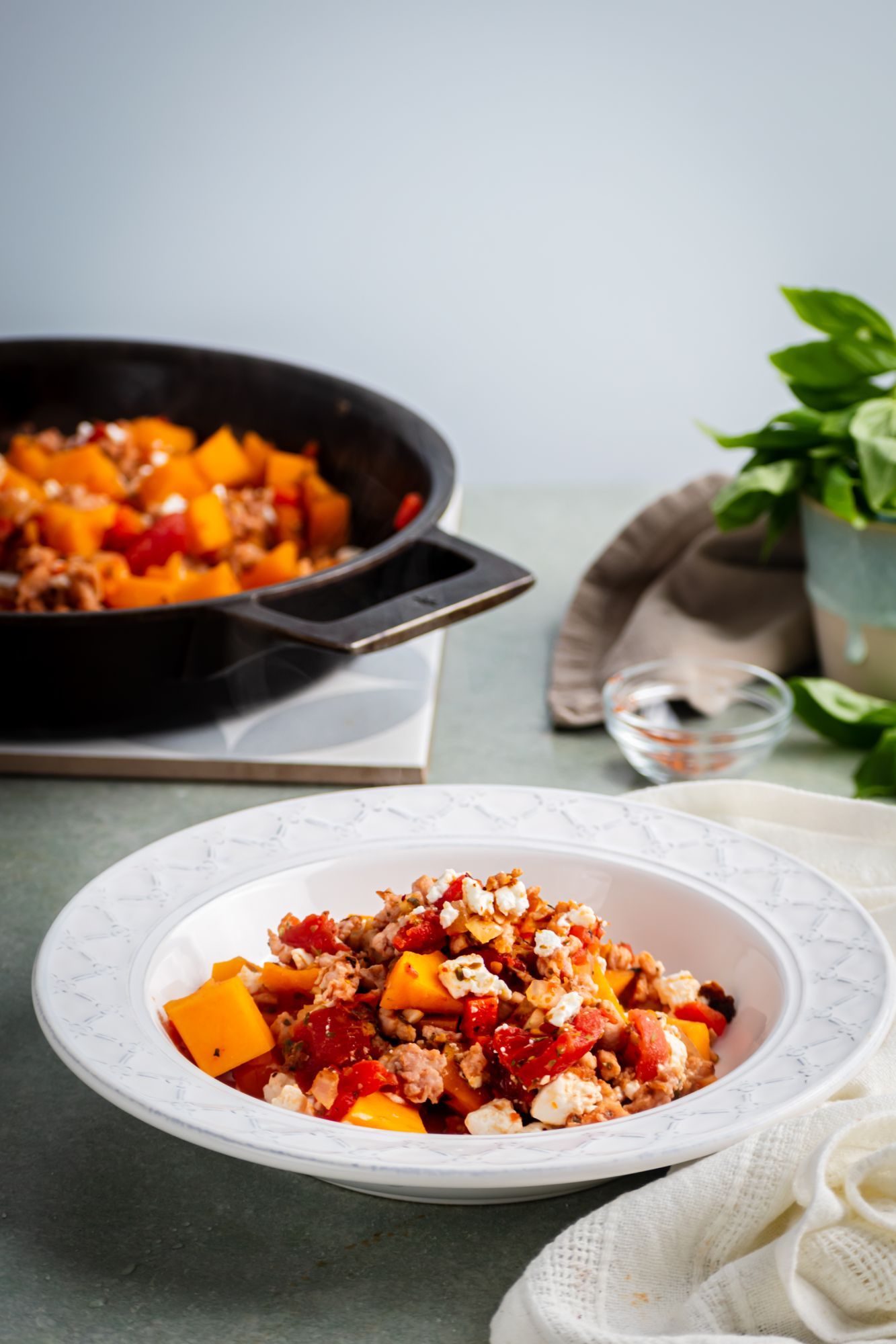 Turkey butternut squash skillet with ground turkey, bell pepper, tomatoes, and feta cheese served on a white plate.