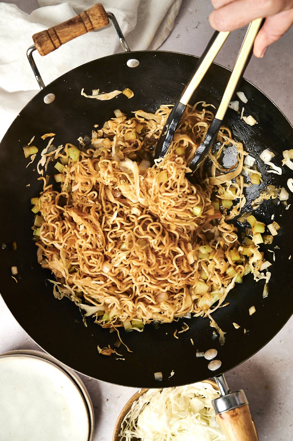 Healthier chow mein being stirred in a wok with tongs.