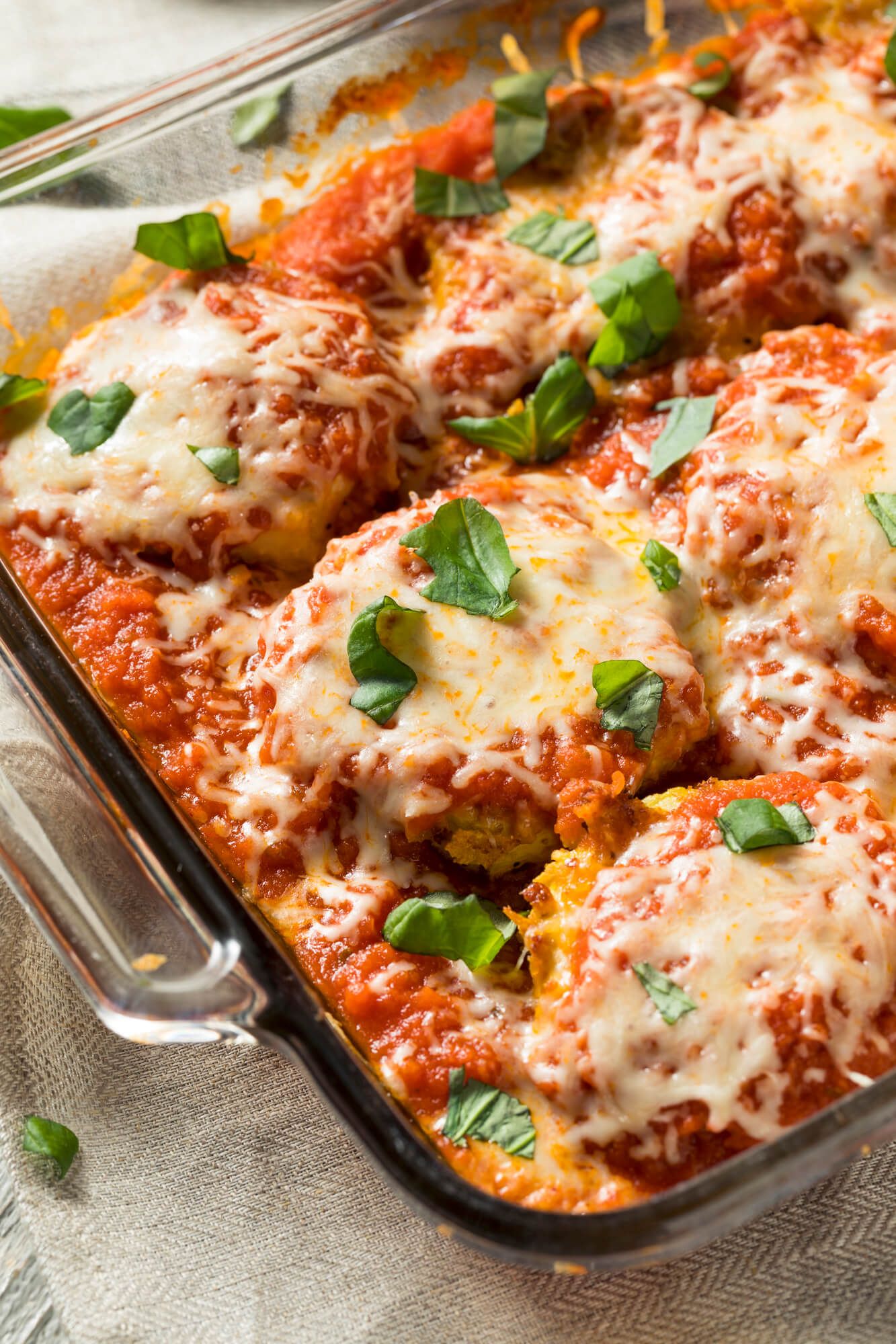 Healthy baked eggplant with marinara sauce and cheese in a glass baking dish.