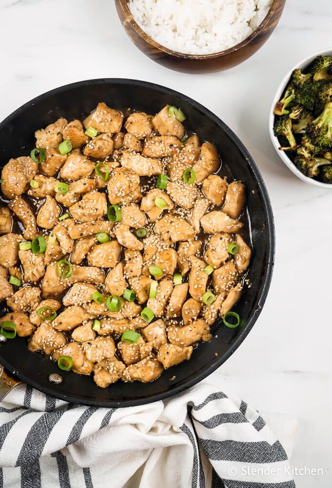 Sesame Chicken with white rice and broccoli topped with sesame seeds and green onions.