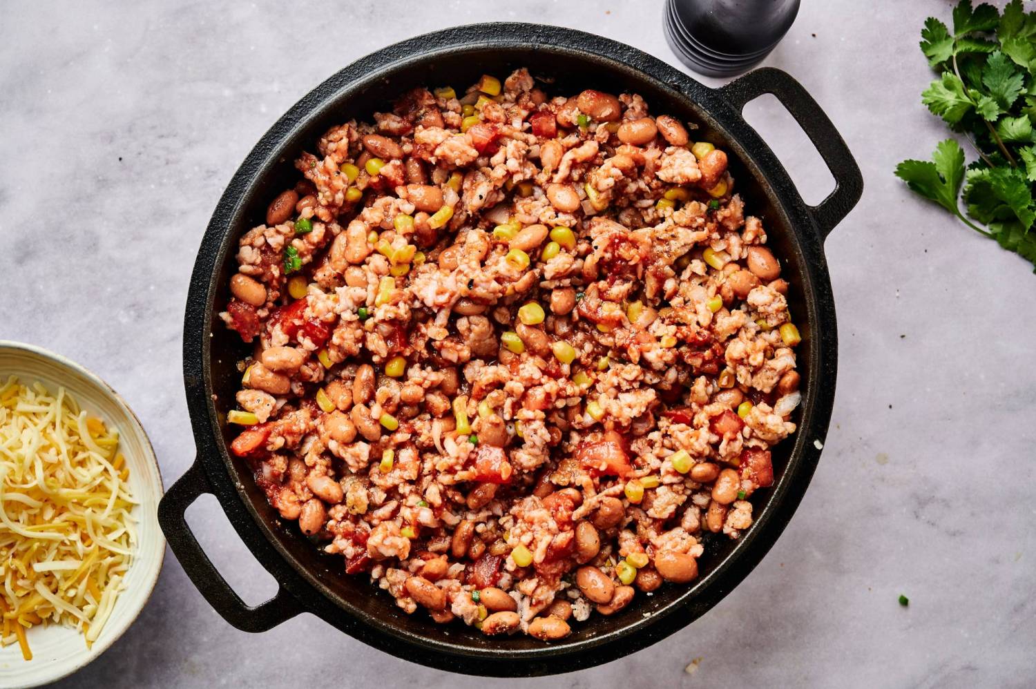Ground turkey, pinto beans, corn, tomatoes, and taco seasoning in a skillet for taco casserole.