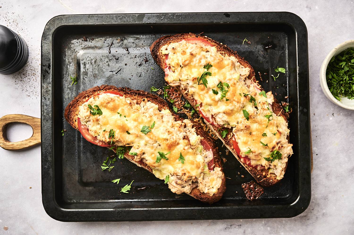 Tuna melts made with whole wheat bread, tomatoes, Greek yogurt tuna salad, and melted cheddar cheese with parsley.