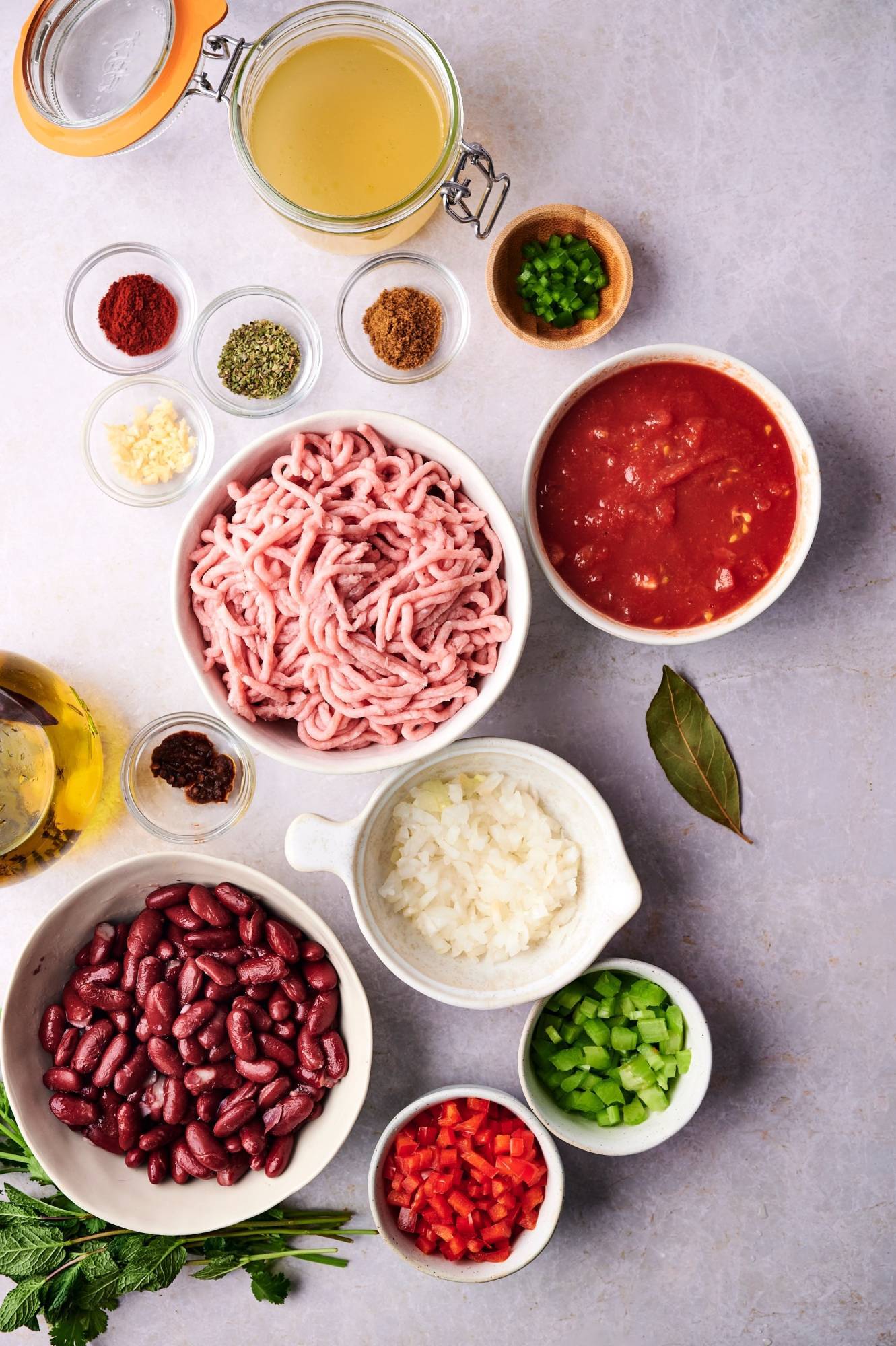 Ingredients for ground turkey chili including ground turkey, onion, bell peppers, celery, tomatoes, and spices. 