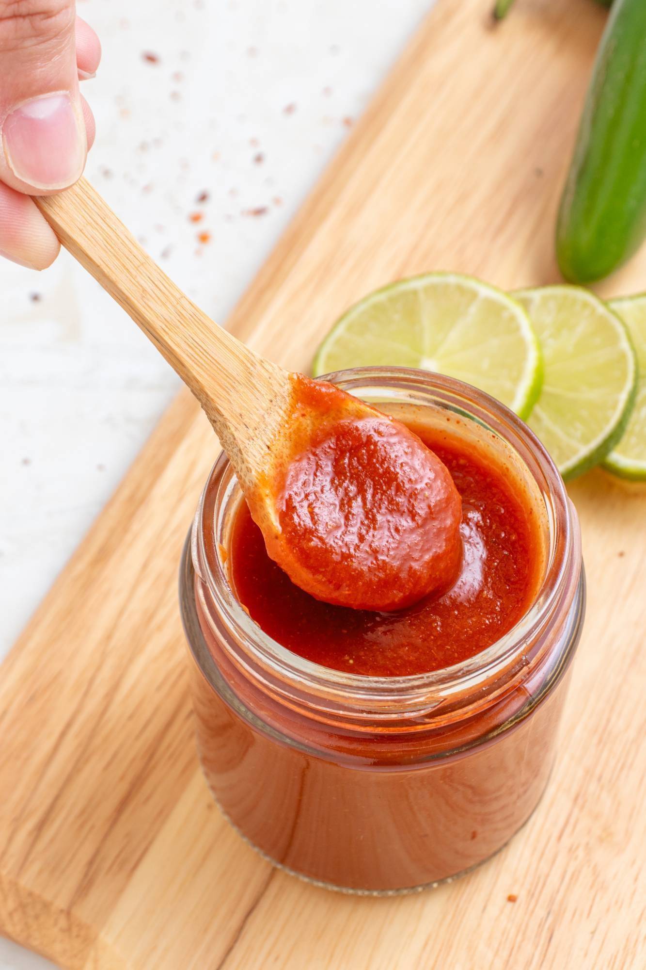 Taco sauce in a small glass jar with a wooden spoon.