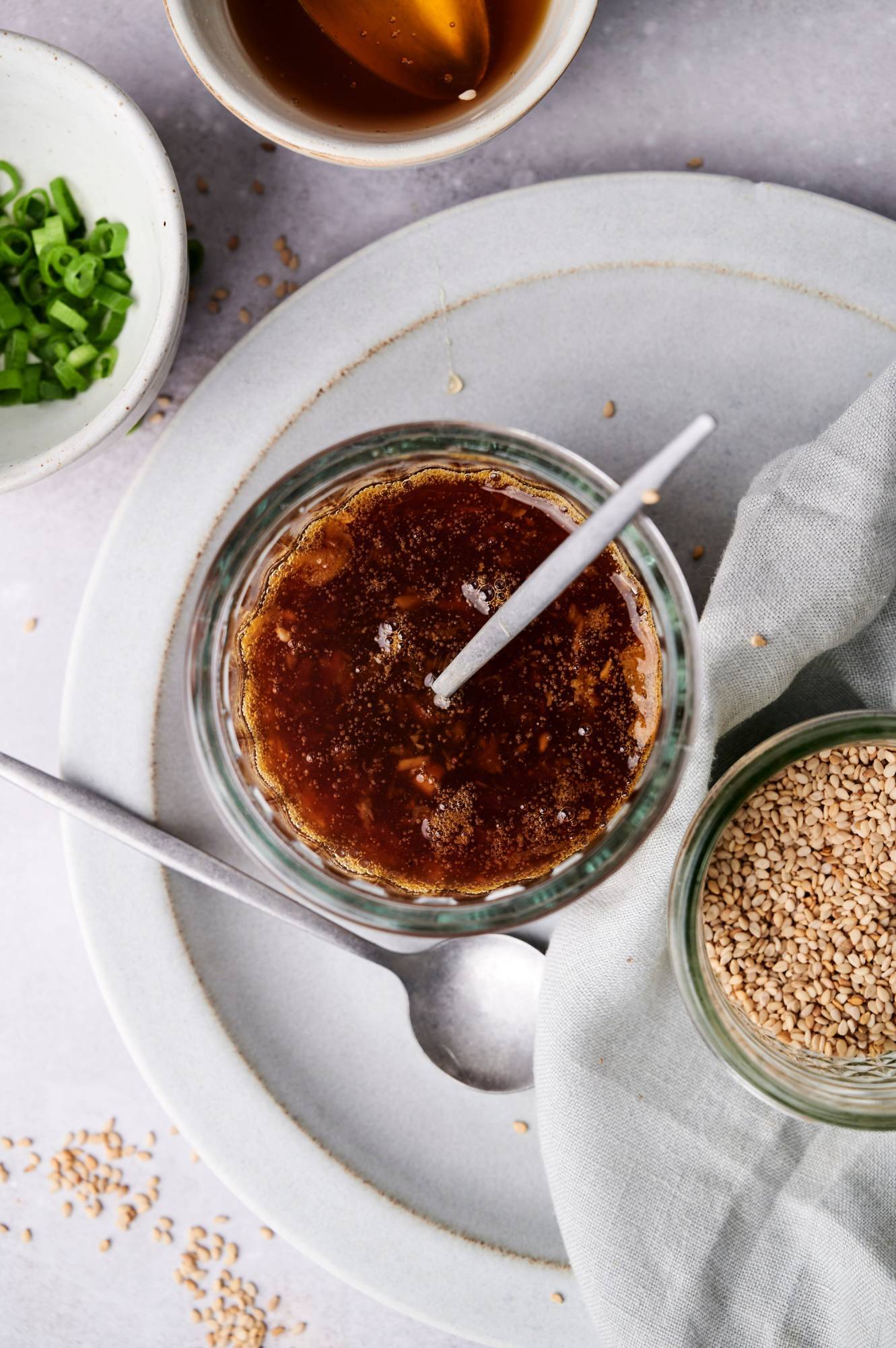 Homemade healthier teriyaki sauce on a plate with sesame seeds on the side.