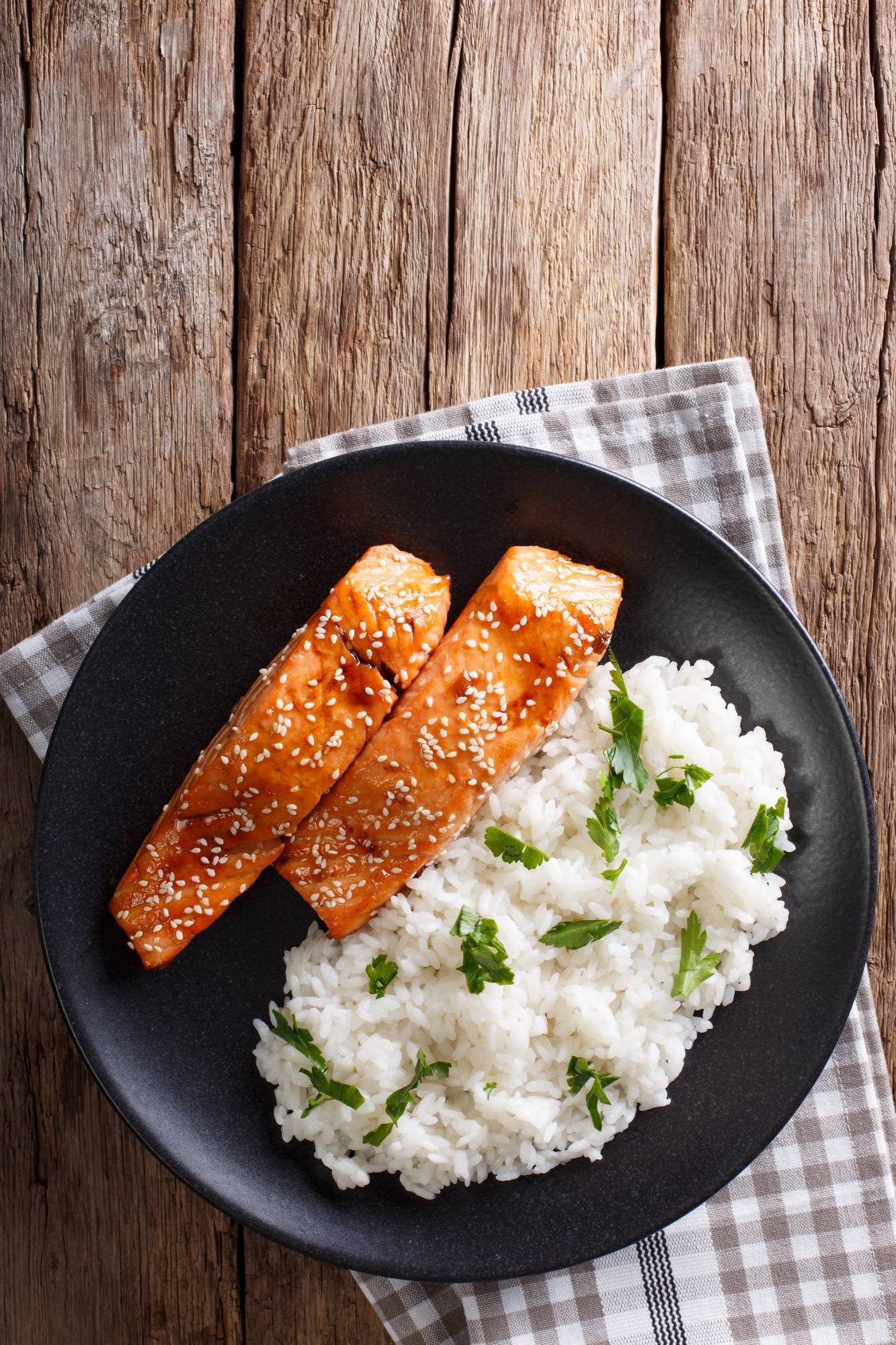 Broiled honey soy salmon served with sesame seeds and green onions on a bed of rice.