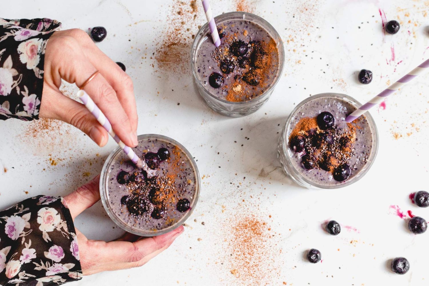 Blueberry banana protein smoothie with chia seeds being held by two hands,