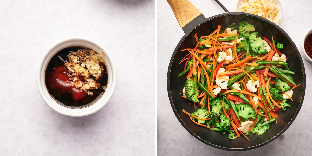 A bowl of sauce with chopped garlic beside a pan of vibrant stir-fried vegetables, including broccoli, carrots, and cauliflower.