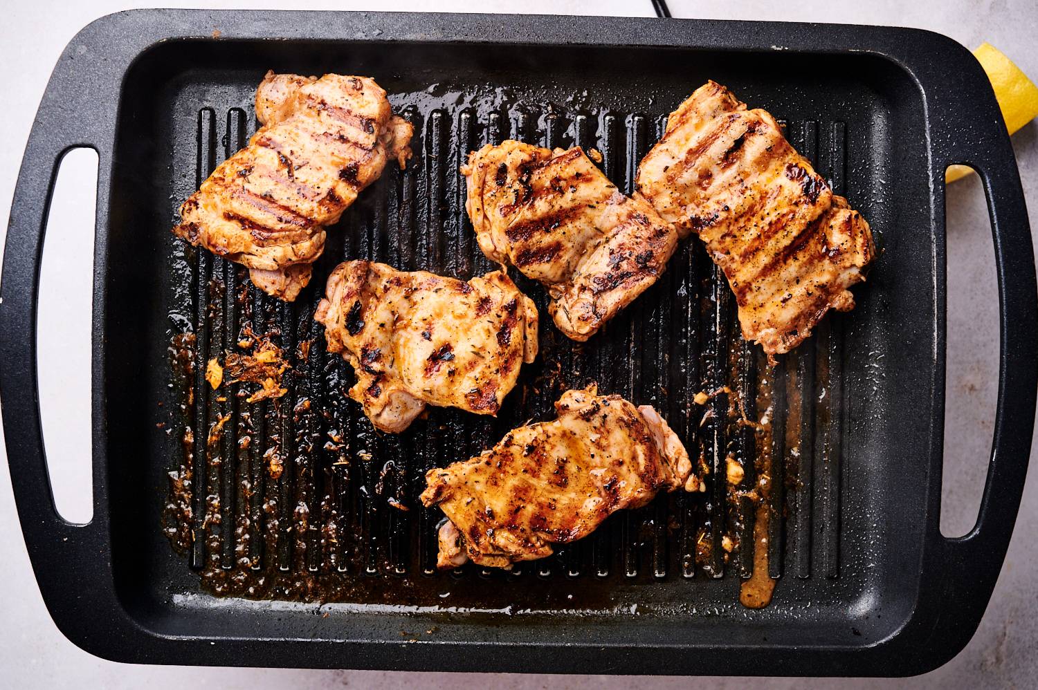 Paprika lemon chicken thighs on a grill pan with brown grill marks.